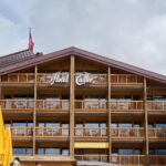 Rustic wooden architecture of Hotel Cailler with balconies and yellow umbrellas in Charmey, Switzerland.