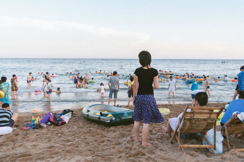 People enjoying a sunny day at the seaside in Qinhuangdao, China, with beach activities and relaxation.