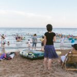 People enjoying a sunny day at the seaside in Qinhuangdao, China, with beach activities and relaxation.