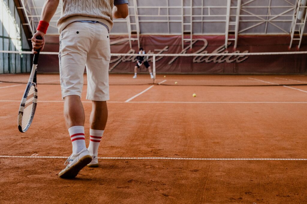 Players competing in a tennis match on an indoor clay court.
