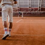 Players competing in a tennis match on an indoor clay court.