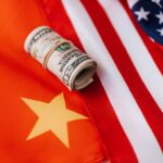 From above of roll of dollar bills tied with rubber band on bright American flag with stars and stripes symbolizing unity and peace