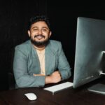Confident businessman sitting at desk, working on computer in modern office.