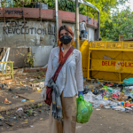 A protester stands in front of a barricade and graffiti at a New Delhi protest site.