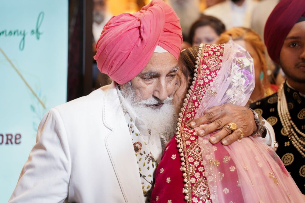 A heartfelt embrace between an elderly man and a bride during a traditional wedding ceremony.