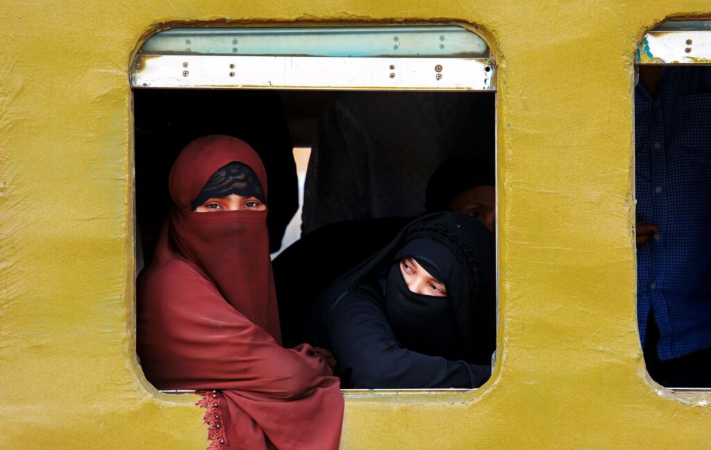 Women in burqas gazing outside a train window in Dhaka, Bangladesh, capturing cultural essence and travel mood.