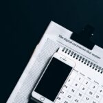 A smartphone placed on a newspaper and calendar, symbolizing modern digital finance.
