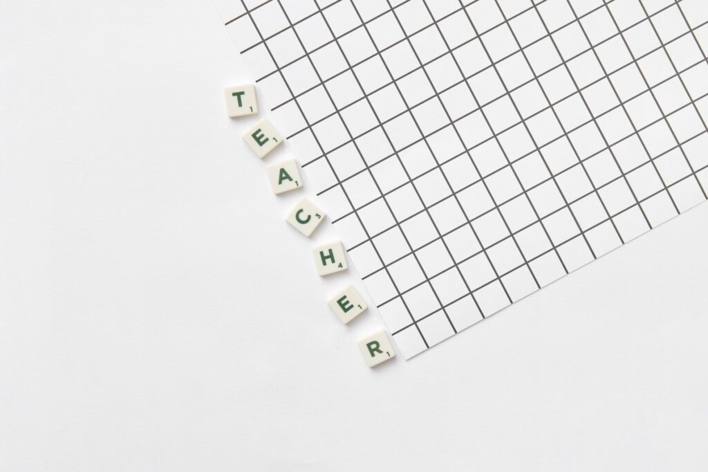 Alphabet letters spelling 'Teacher' on a white grid paper, highlighting education theme.