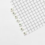 Alphabet letters spelling 'Teacher' on a white grid paper, highlighting education theme.