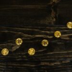 Gold-colored bitcoins arranged diagonally on a dark wooden surface.