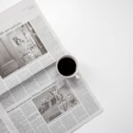 A fresh cup of coffee resting on a newspaper, perfect morning routine setup.