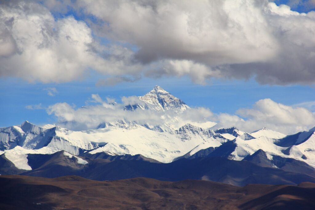 Beautiful snow-covered mountain peaks under fluffy clouds, showcasing nature's grandeur.