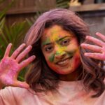 Cheerful woman with vibrant holi powder on face, enjoying the festival.