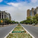 A vibrant urban scene in New Delhi, showcasing modern architecture and a wide, empty road.
