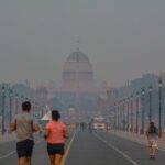 People jogging in smog near Rashtrapati Bhavan, New Delhi, highlighting urban pollution.