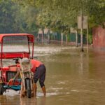 A rickshaw navigates a flooded street in New Delhi, India, during the 2023 monsoon.
