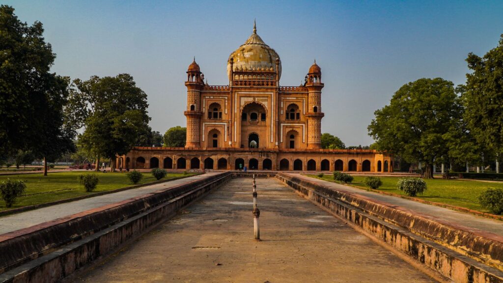 Stunning view of Safdarjung Tomb in New Delhi, India, captured at sunset with clear skies and lush greenery.