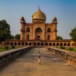Stunning view of Safdarjung Tomb in New Delhi, India, captured at sunset with clear skies and lush greenery.