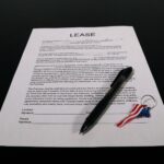 Lease agreement document with pen and American flag keychain on a black table.