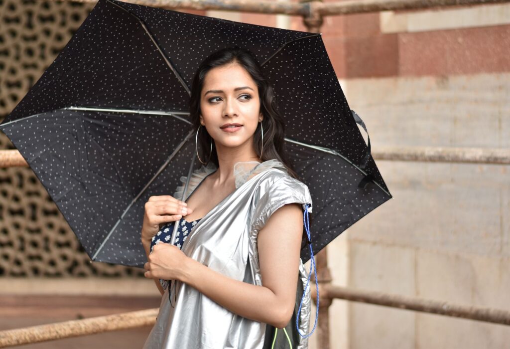 Captivating portrait of a stylish woman with umbrella, outdoors in New Delhi, India.