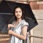 Captivating portrait of a stylish woman with umbrella, outdoors in New Delhi, India.
