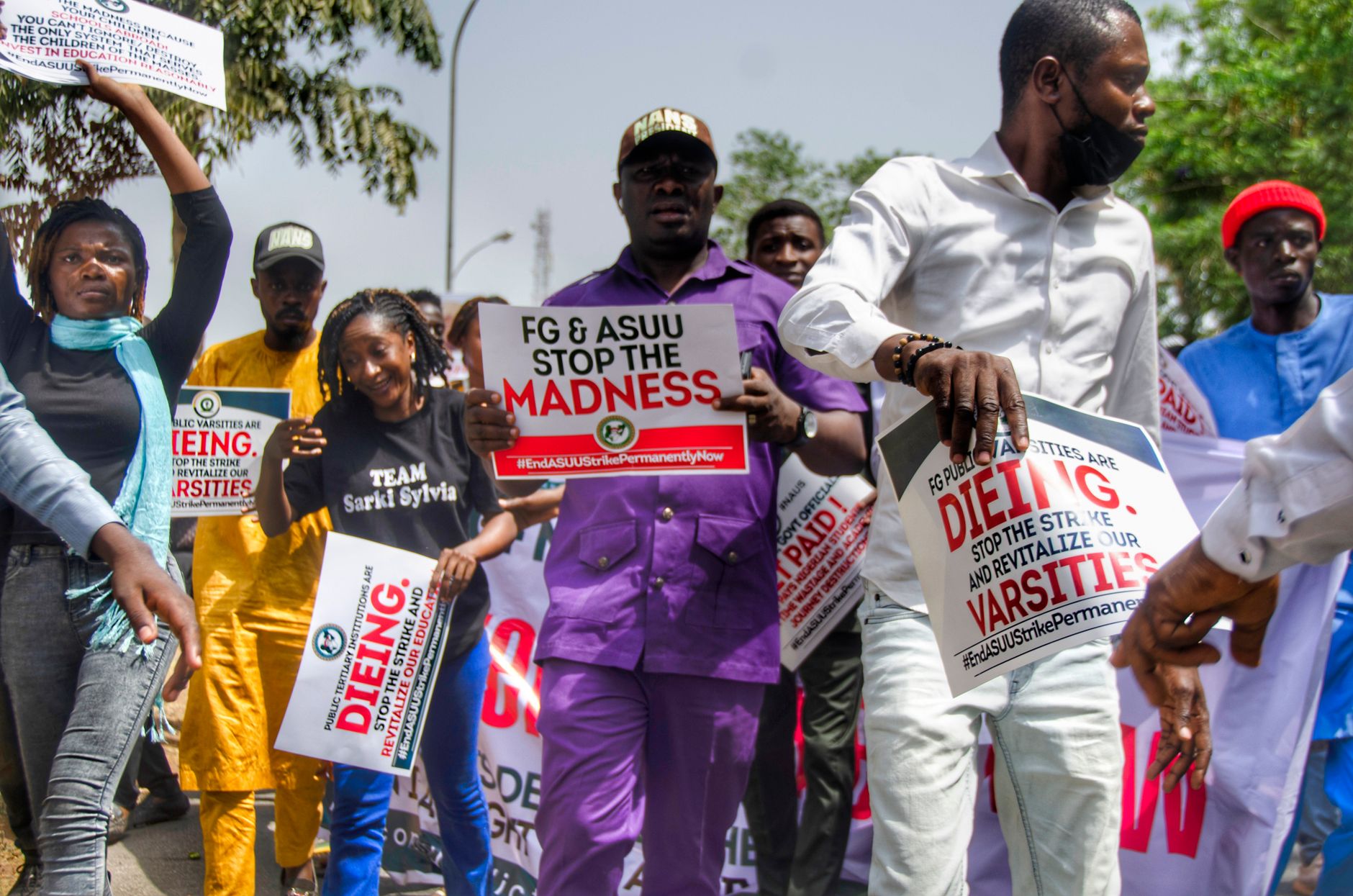 A group of people protesting with signs demanding change. Focus on educational reform.
