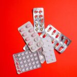 Blister packs with assorted pills over a vibrant red surface. Ideal for healthcare themes.