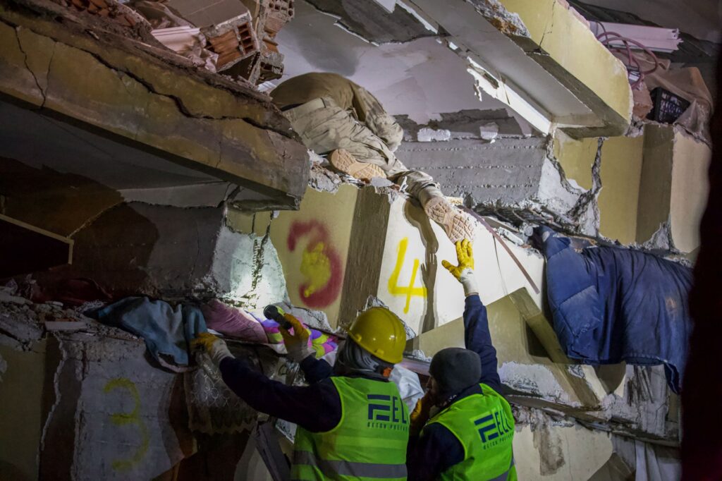 Emergency responders rescuing a person trapped in a collapsed structure during a nighttime operation.