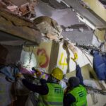 Emergency responders rescuing a person trapped in a collapsed structure during a nighttime operation.
