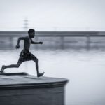 A young man in mid-air leaping over water, capturing the essence of freedom and dynamic movement.
