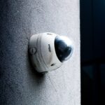 Close-up view of a dome security camera mounted on a concrete wall for surveillance.