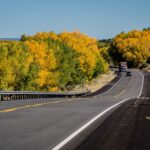 Scenic autumn drive through Ojo Caliente, New Mexico with vibrant fall foliage and empty highway.