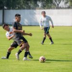 Players in an intense football match, showcasing teamwork and skill on the green field.
