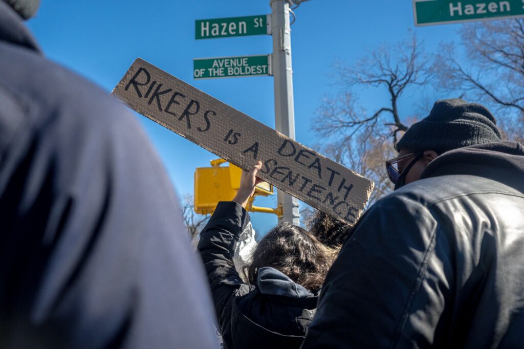 Protest at New York intersection with sign 'Rikers is a death sentence'.