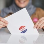 Close-up of hands holding a vote ballot, symbolizing election participation.