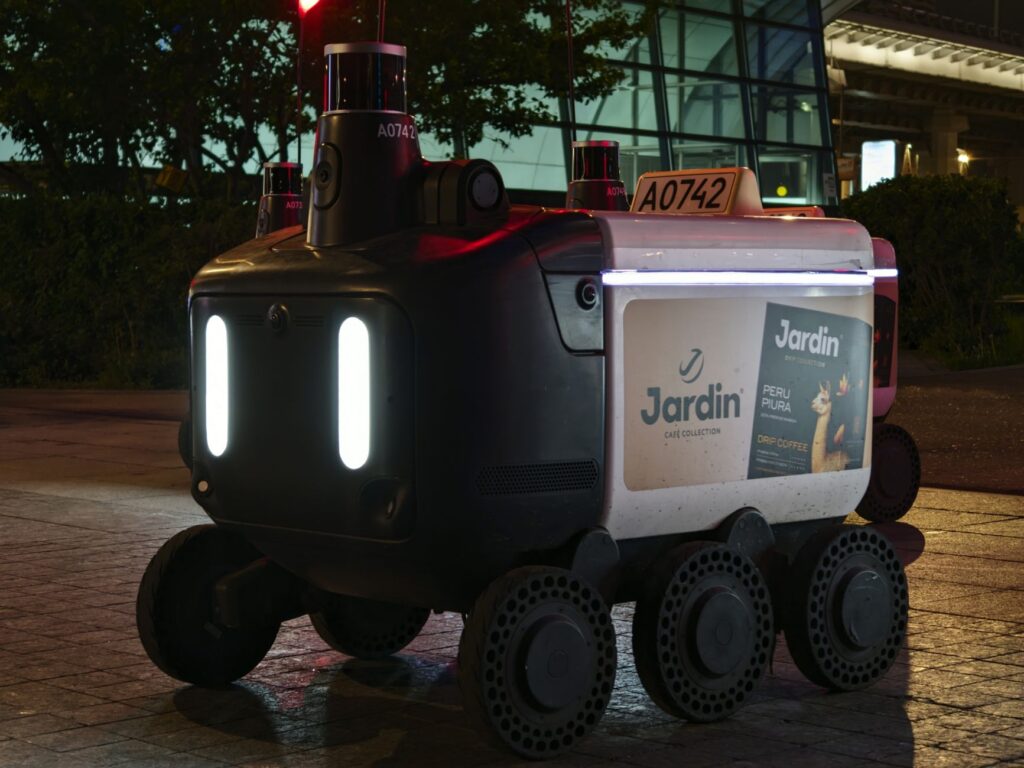 Close-up view of an autonomous delivery robot on a city street at night under artificial light.