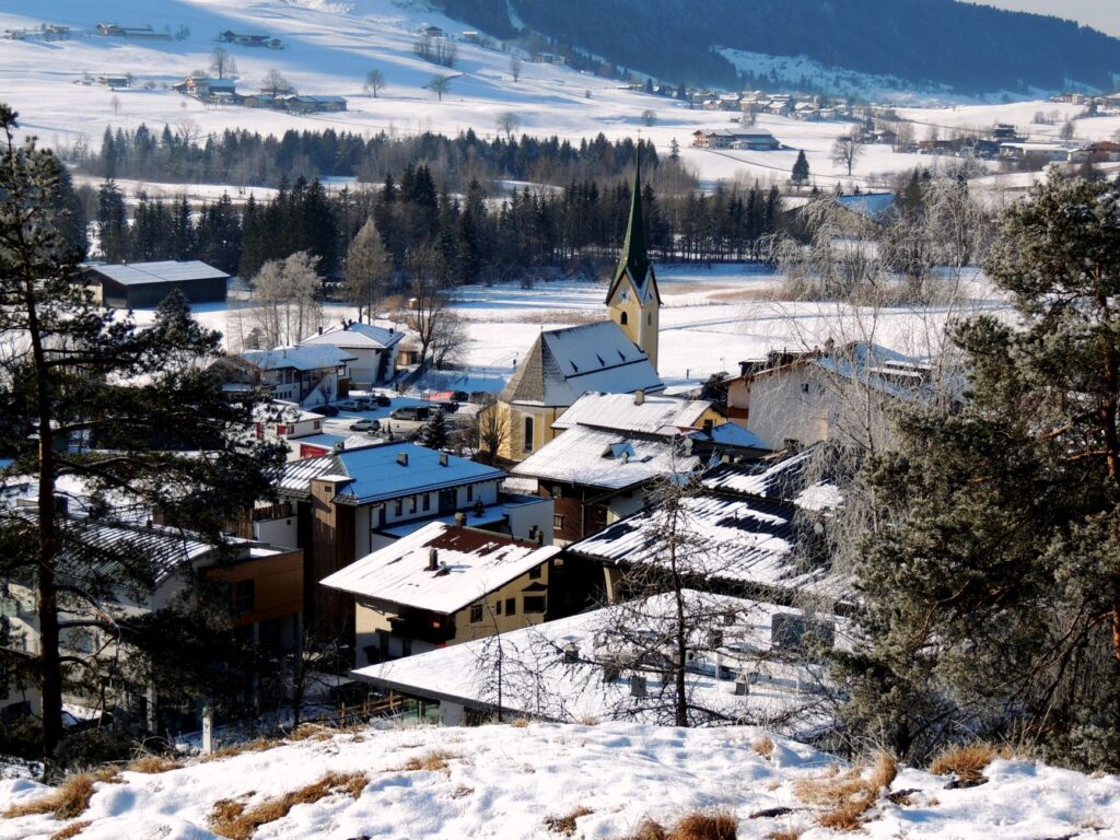 Scenic winter view of Walchsee village with snow-covered houses and church in Tirol, Austria.