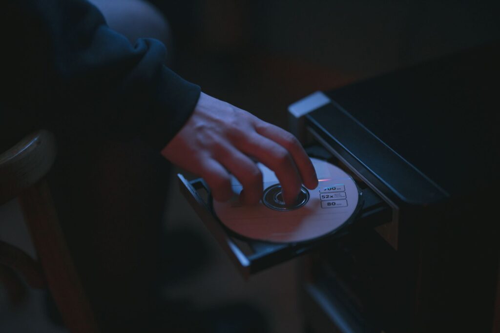 A hand inserting a CD into a computer drive, highlighting cyber security themes.
