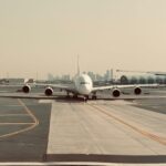 A large airplane on the tarmac at Dubai International Airport with city skyline in the background.