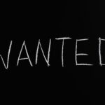 Black chalkboard with 'Wanted' written in white chalk, ideal for hiring or job concept visuals.