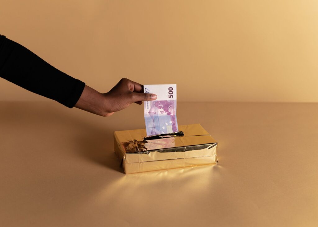 Euro banknote held by a hand against beige background, symbolizing bribery or gifting.