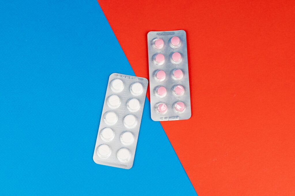 Flat lay of pill blister packs on a red and blue surface, ideal for healthcare themes.