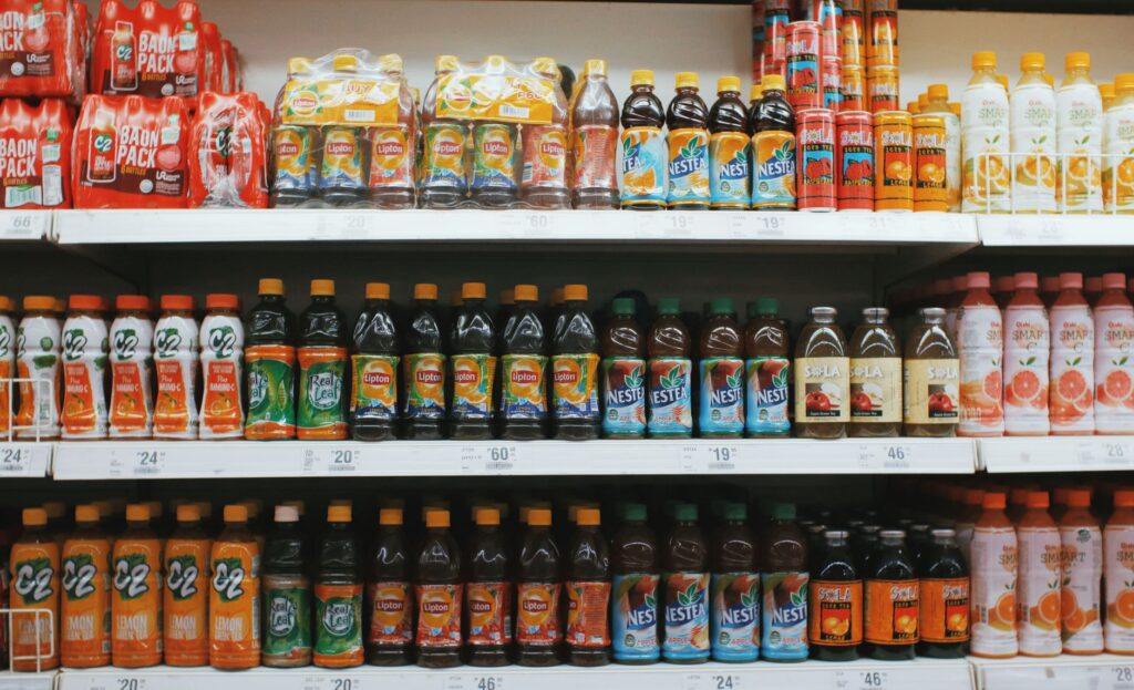 Rows of colorful plastic bottles with lemonades placed on light shelves in supermarket