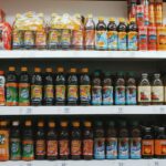 Rows of colorful plastic bottles with lemonades placed on light shelves in supermarket