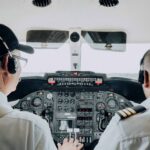 Close-up view of two pilots managing the cockpit controls of an aircraft, focusing on instrumentation.