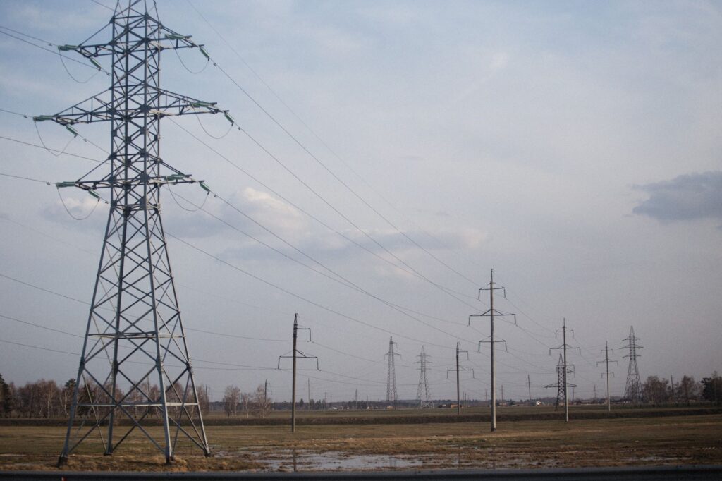 Power lines stretch across a field in autumn, highlighting energy infrastructure.