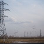Power lines stretch across a field in autumn, highlighting energy infrastructure.