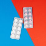 Flat lay of pill blister packs on a red and blue surface, ideal for healthcare themes.