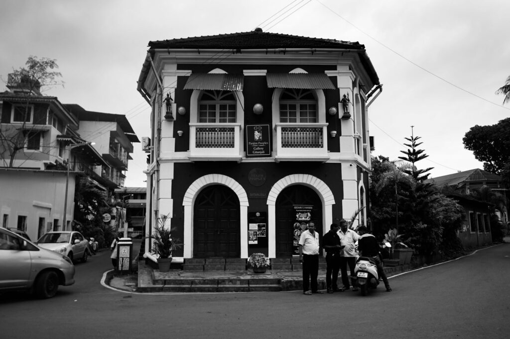 Monochrome image of a vintage colonial building with people in an urban setting.