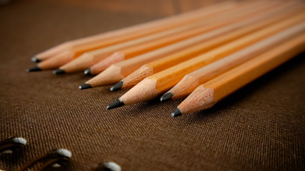 A detailed view of sharpened wooden pencils placed on a textured fabric background, showing artistry and precision.